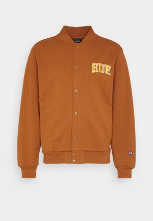 Brązowa kurtka varsity zapinana na guziki, z prążkowanymi mankietami i spodem, z żółtymi literami "HUF" na piersi oraz małym okrągłym logo na rękawie.