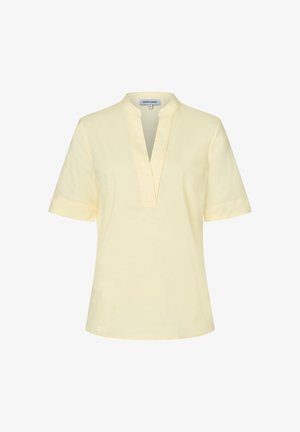 Blouse jaune clair à manches courtes avec un profond col en V et un col montant, présentée sur un fond blanc uni.