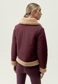 Burgundská prošívaná bunda s texturovaným krémovým umělým kožíškem na límci a manžetách, s cropped designem a hladkým materiálem na těle.