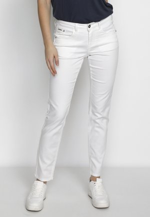 Vita slim-fit jeans med normal midja, fem fickor och subtila sömnadsdetaljer, tillsammans med vita sneakers.