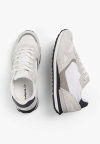 Zapatillas blancas y grises que combinan materiales de ante y malla, con acentos texturizados y una suela de goma negra.