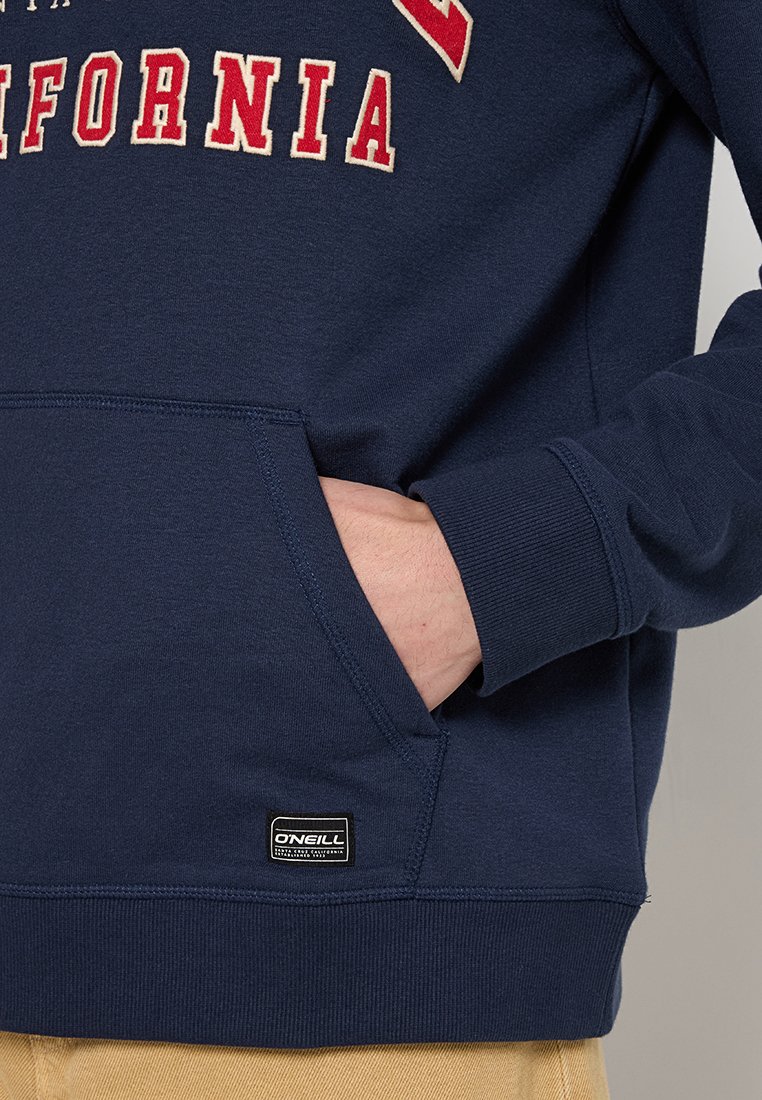 Marineblauer Sweatshirt mit Fronttasche, gerippten Bündchen und Saum. Mit "California" in roter und cremefarbener Schrift. Enthält O'Neill-Logo-Patch.