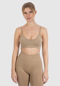 Lysebrunt atletisk crop top med tynde stropper og sømløst design, parret med højbundet matchende leggings med subtil branding.