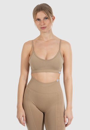 Lichtbruin atletisch crop top met dunne bandjes en een naadloos ontwerp, gecombineerd met bijpassende high-waisted leggings met subtiele branding.