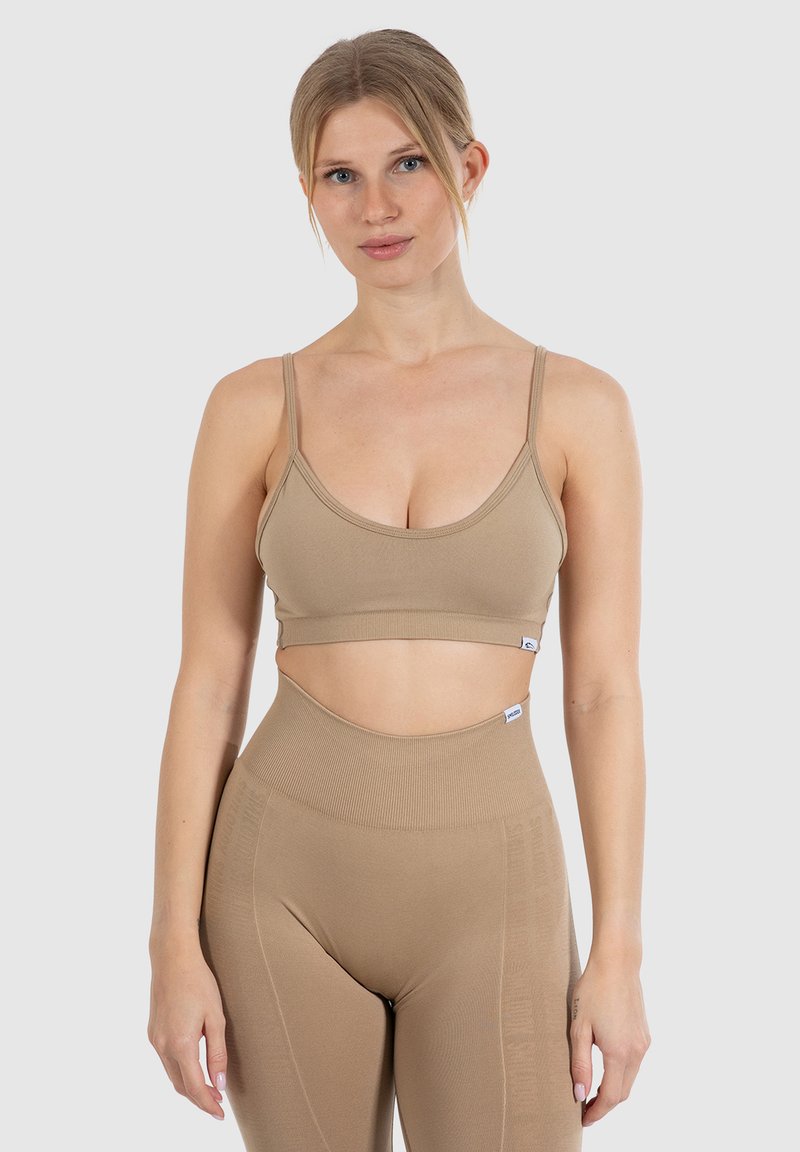 Lysebrunt atletisk crop top med tynde stropper og sømløst design, parret med højbundet matchende leggings med subtil branding.