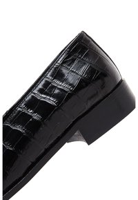 Schwarze Leder-Slipper mit strukturiertem Krokodil-Muster, niedrigem, stabilen schwarzen Absatz und glatten Kanten.