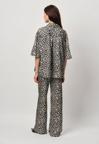Two-piece outfit in leopard print, featuring a loose-fitting short-sleeve shirt and wide-leg pants, made of lightweight fabric.
