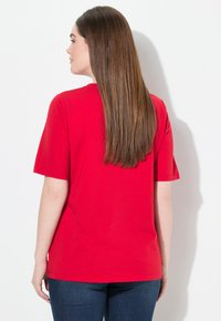 Camiseta de manga corta roja con cuello redondeado, material de algodón suave y un ajuste relajado, mostrada desde la parte de atrás.