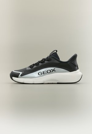 Baskets Geox noires et blanches avec une semelle blanche épaisse, un accent argenté sur le côté et des lacets noirs, vues de côté.
