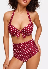 Rood bikini met stippen, haltertop en strikdetail. Hoog tailleonderdeel met een elastische tailleband en geplooid ontwerp aan de zijkanten.
