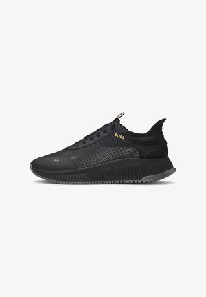 Black athletic sneakers with mesh paneling, textured sole, and prominent logo. Features a sleek design and padded heel for comfort.