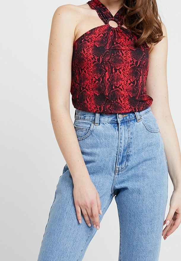Czerwono-czarny top halter w wzór węża z okrągłym detalem hardware przy dekolcie, zestawiony z jasnoniebieskimi dżinsami o wysokim stanie.