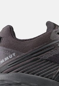 Schwarzer Sport- Schuh mit einem texturierten Stoffobermaterial im Rippmuster, gepolstertem Kragen und einer strapazierfähigen Gummisohle.