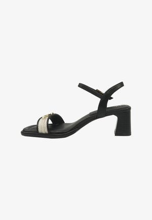 Black mid-heel sandal with ankle strap, featuring a textured beige and gold decorative band across the toe.