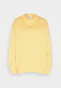 Gul sweatshirt i mjukt tyg, med rund halsringning, sänkt axelsöm, ribbade muddar och en liten silverlogotyp på bröstet.