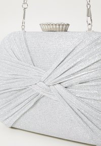 Borsa a pochette in argento, caratterizzata da un design a pieghe con texture, chiusura superiore decorata con gemme e una tracolla rimovibile.