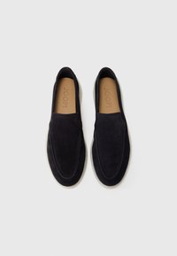 Mustad musta suede'ist libiseva nagu kingad, millel on sile pind, ümar nina, kontrastsete valgete kummitaldadega ja reljeefne brändi logo jalamatil.