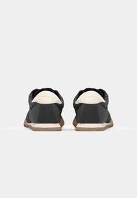 Scarpe sportive nere con controspacco bianco e suola in gomma naturale, caratterizzate da un tessuto testurizzato e un design a profilo basso e snello.