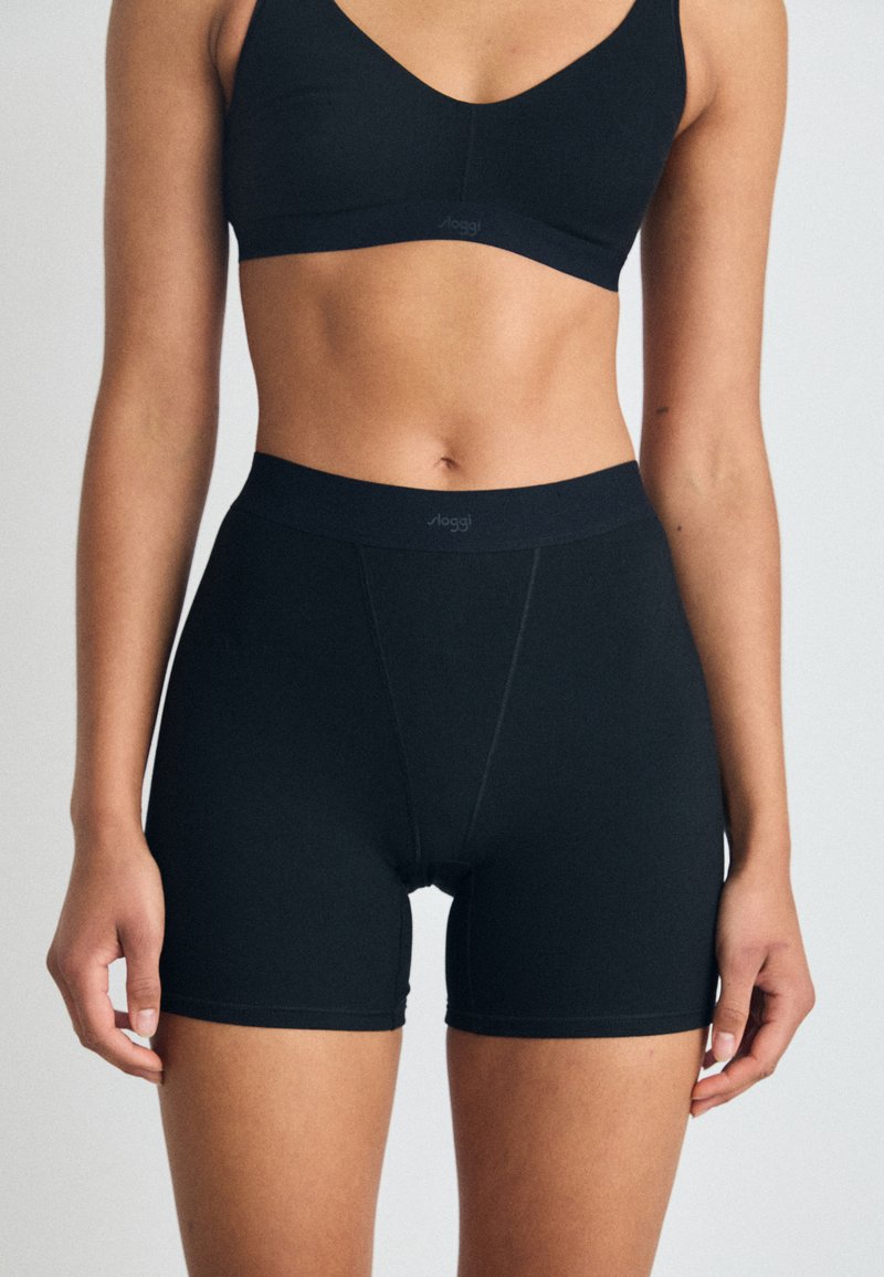 Schwarzer nahtloser BH und hochgeschnittene Shorts aus weichem Stretchmaterial. Verfügt über eine glatte Oberfläche und minimale Nähdetails.