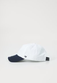 White baseball cap with navy brim, adjustable strap, embroidered logo on front, and subtle stitching details. Cotton material, casual design.