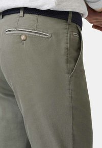 Khaki bukser med en glat tekstur, der har en knaplomme og kontrasterende syninger. Designet med sidelommer og en moderne pasform.