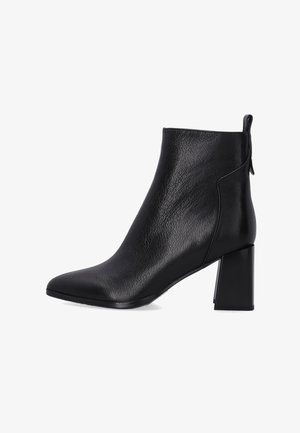 Schwarze Leder-Ankle-Boots mit spitz zulaufender Zehenpartie, strukturierten Oberflächen und einem klobigen, rechteckigen Absatz. Mit einer kleinen Ziehlasche hinten für ein einfaches Anziehen.
