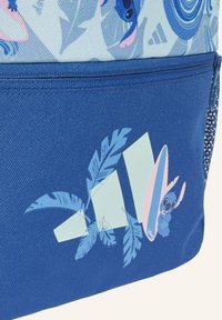 Mochila azul con una sección inferior texturizada, una parte superior de un azul claro con un patrón que presenta gráficos de un personaje y plantas, y un acento con formas de tabla de surf.