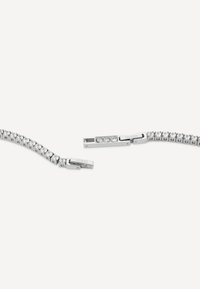 Silberarmband mit einer Reihe klarer Strasssteine, flexiblem Design und einem rechteckigen Verschluss, der mit dem Markennamen "GUESS" graviert ist.