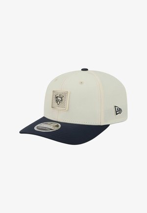 Beige und marineblaue Baseballkappe mit aufgenähtem Bärenlogo vorne und New Era-Logo an der Seite, dargestellt auf weißem Hintergrund.