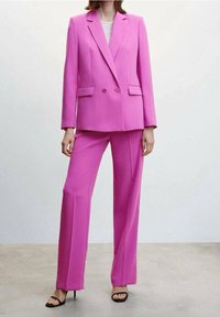 Světlý růžový blazer s klopami a dvouřadým zapínáním v kombinaci s kalhotami širokého střihu ve stejné barvě. Hladká látka a dobře padnoucí střih.