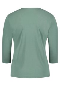 Zelený dlouhý rukáv top vyrobený z jemné látky; má oválný výstřih a je navržen v uvolněném střihu. Zadní pohled ukazuje hladkou strukturu.