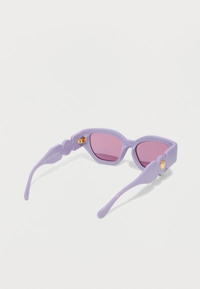 Παντελόνια γυαλιά ηλίου με μοβ σκελετό σε σχήμα γάτας, ροζ φακούς και χρυσές διακοσμητικές λεπτομέρειες στα πλαϊνά του σκελετού, τοποθετημένα σε λευκή επιφάνεια.