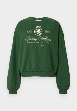Green cropped sweatshirt with long sleeves, featuring embossed white text and lion crest design. Ribbed cuffs and hem, soft fabric texture.