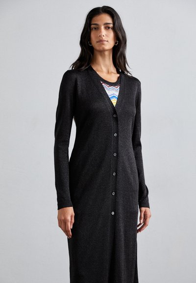 Cárdigan largo negro de tejido de punto con un ligero brillo, con escote en V, mangas largas y cierre de botones en la parte delantera.
