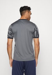 Grijze sportshirt met korte mouwen, voorzien van een gestructureerd zwart patroon op de schouders. Gladde stof en een klassiek ronde hals ontwerp.