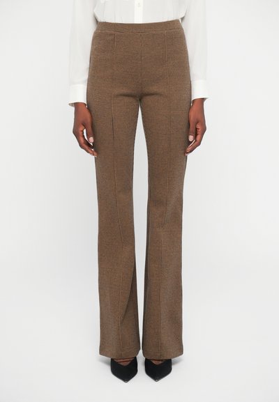 Brown checkered pants with a flared shape, featuring a textured fabric and a high waist. Paired with black pointed-toe shoes.
