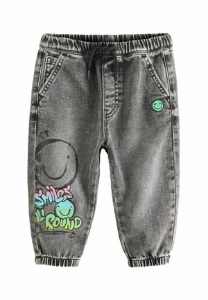 Pantalon de jogging en denim noir avec une taille élastique, un cordon de serrage, et des motifs graphiques de smileys verts et bleus sur la jambe gauche.