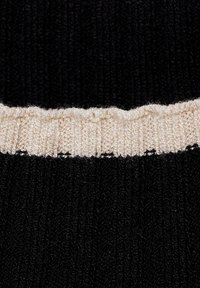 Strikket sweater med en struktureret sort krop og en kontrasterende ribbet cremefarvet halsudskæring. Glat stof med et sømløst design.