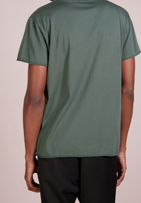 Mörkgrön kortärmad t-shirt med en avslappnad passform, tillverkad av mjuk bomull. Har en rundad halsringning och minimala sömnadsdetaljer.