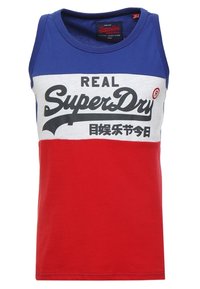 Camiseta sin mangas con un diseño de bloques de color azul y rojo, con una sección media blanca que muestra texto en negrita en negro y rojo. Material de algodón.
