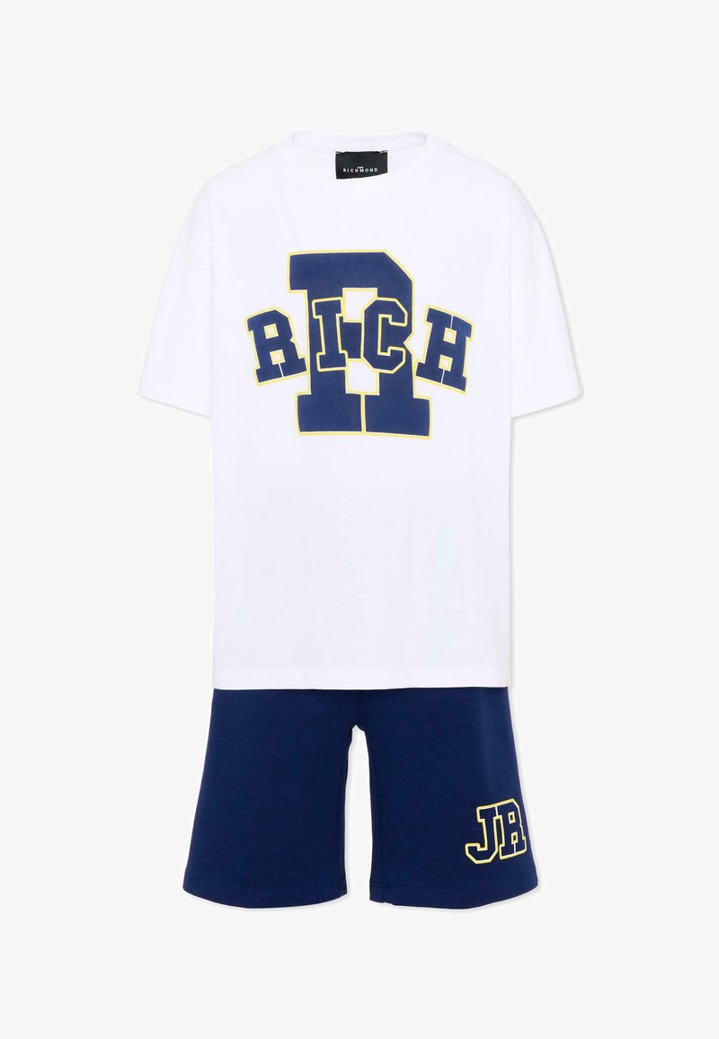 T-shirt blanc à manches courtes avec un grand logo "RICH" bleu bordé de jaune, associé à un short bleu avec des lettres "JR" bordées de jaune.