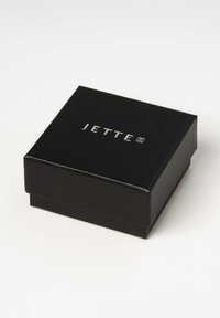 Schwarz glänzende Schmuckschatulle mit einer strukturierten Oberfläche, auf dem Deckel befindet sich ein silbernes "JETTE"-Logo. Quadratische Form mit einem glatten, geschlossenen Design.