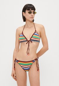 Kleurige gestreepte gehaakte bikini met een driehoekige top met bruine strikjes en bijpassende onderbroek, beide versierd met kleine accentparels.