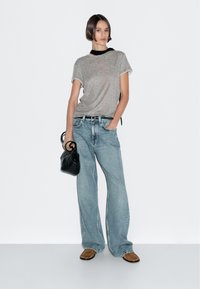 Gray short-sleeve t-shirt, light blue wide-leg jeans, brown footwear, and a small black handbag, set against a plain white background.