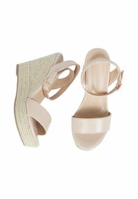 Sandali con zeppa beige, dotati di cinturini larghi e di una cinghia alla caviglia con fibbia. Suola in corda di texture naturale. Parte superiore in materiale sintetico liscio con finitura lucida.