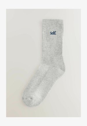 Gray ribbed socks with a light texture, featuring the word "self" embroidered in navy blue. The design includes a standard sock shape and length.