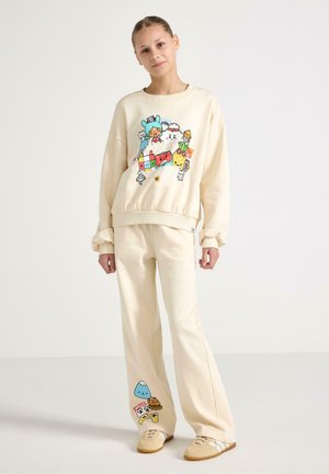 Felpa color crema chiaro e pantaloni abbinati, con grafiche colorate in stile cartone animato. Tessuto morbido, vestibilità comoda e dettagli curati su entrambi i capi.