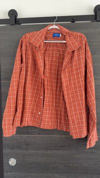 Camicia a maniche lunghe a quadretti rossi e bianchi con colletto a punta e una tasca sul petto. Tessuto di cotone, vestibilità comoda.