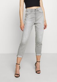 Jeans de denim gris con un corte ajustado, puños enrollados y sutiles detalles de salpicaduras de pintura. Presentan un diseño clásico de cinco bolsillos y cierre de botón.