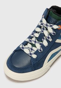 Blauwe high-top sneaker van suede met witte accenten, gestructureerde veters met een blauw-wit patroon en een groene voering aan de binnenkant.